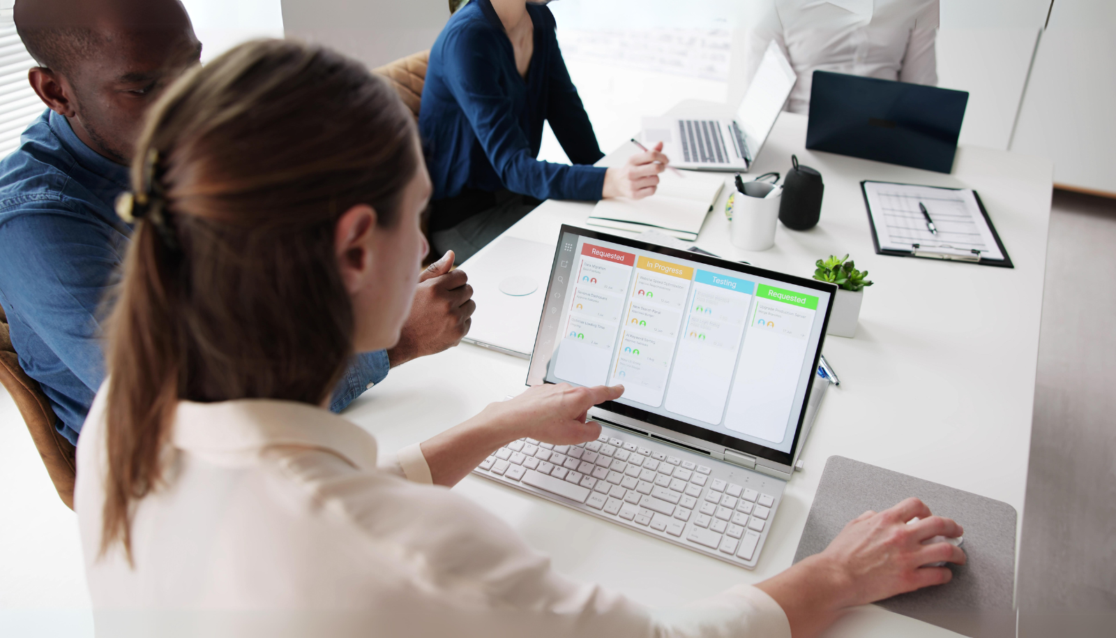 Team members reviewing a project board on a laptop during a planning meeting